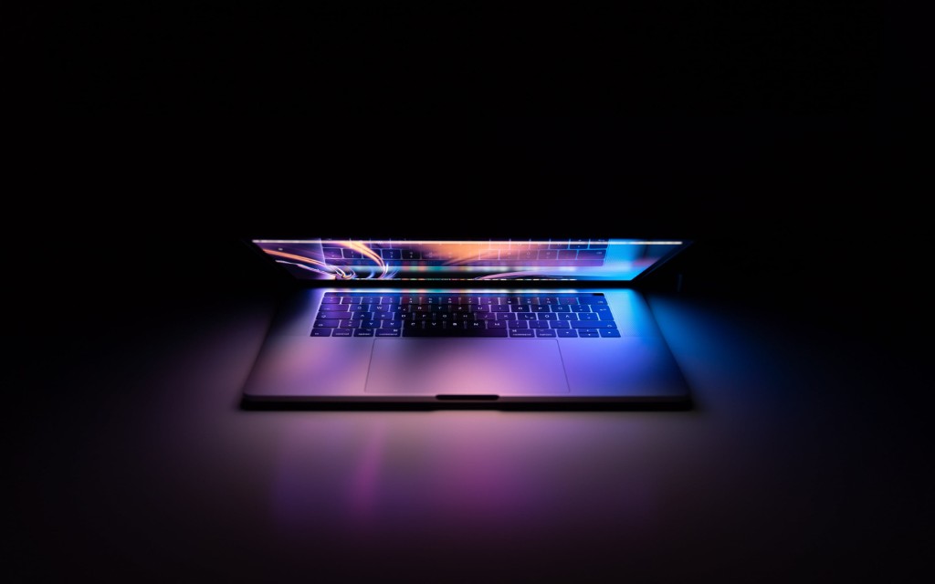 Laptop open on a dark surface with soft accent lighting